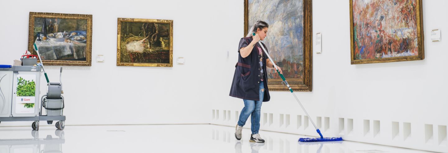 schoonmaakster dweilt witte vloer in museum